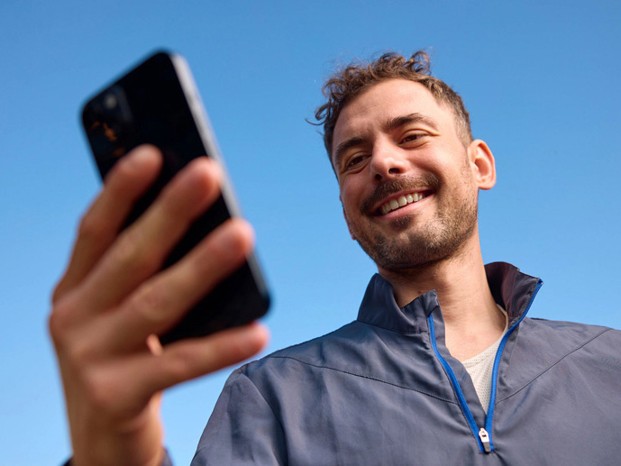 Un homme tient son téléphone en souriant.