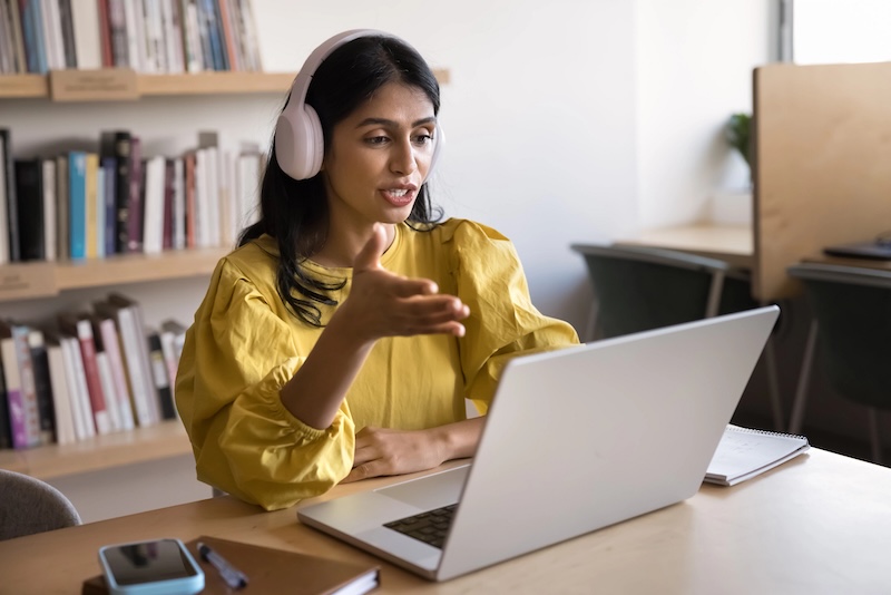 Woman wearing headphones speaking on a virtual meeting