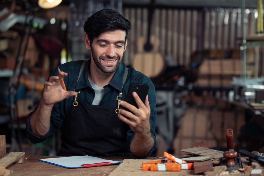 A man in his workshop using his phone