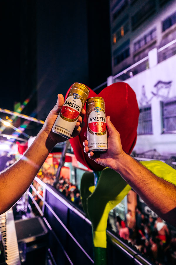 Two people toasting one another using Amstel beer