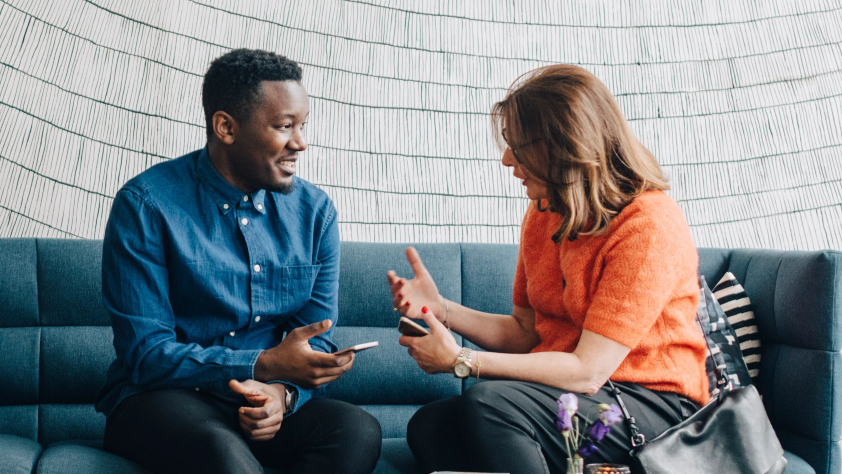 Two people sitting on a couch and engaging in conversation