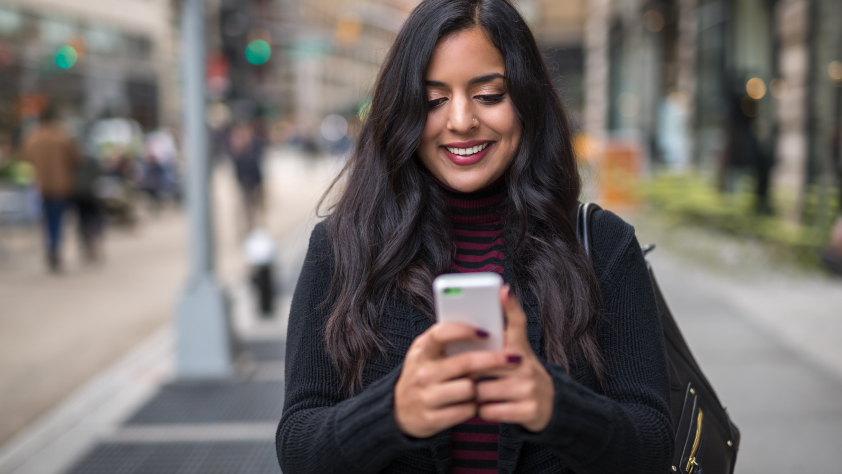 Une personne marchant dans la rue lit un message professionnel sur WhatsApp