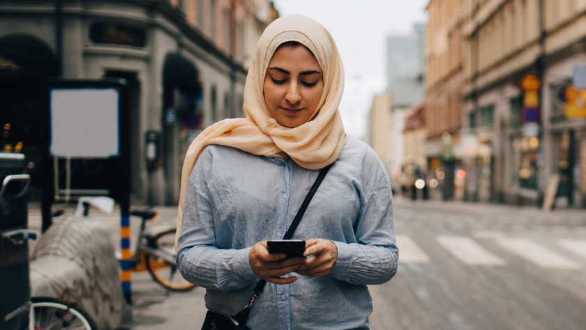 Persona caminando por la calle leyendo un mensaje de WhatsApp en el teléfono