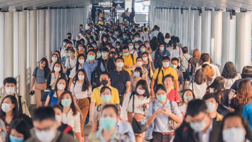 Un grand groupe de personnes portant des masques sort d’une station de transports en commun