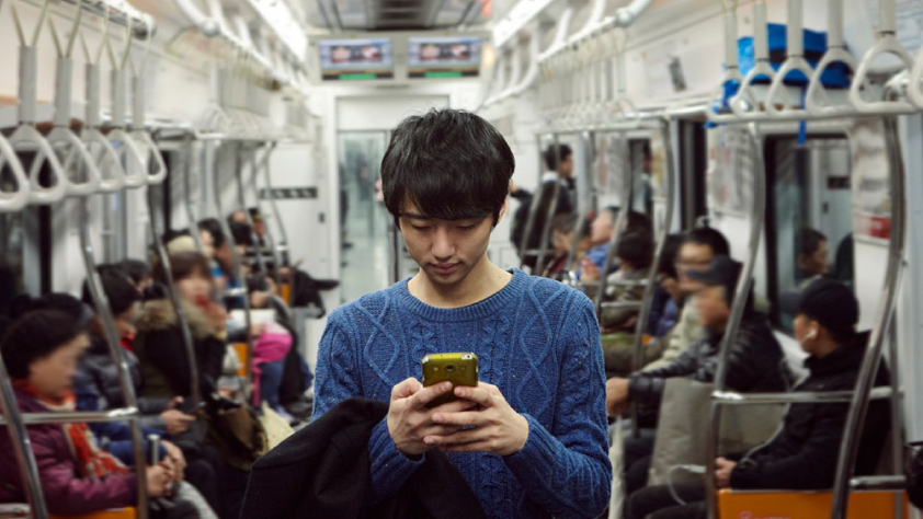 Person standing in middle of bus while reading a WhatsApp message