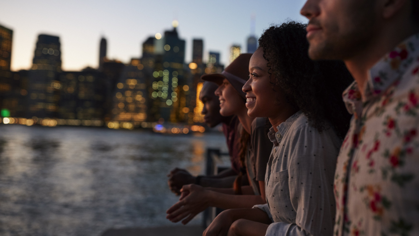Quatre personnes debout sur le ponton à New York, au coucher du soleil