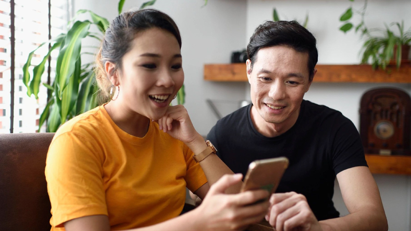 Dua orang duduk di ruang keluarga sambil berinteraksi dengan iklan klik untuk mengirim pesan