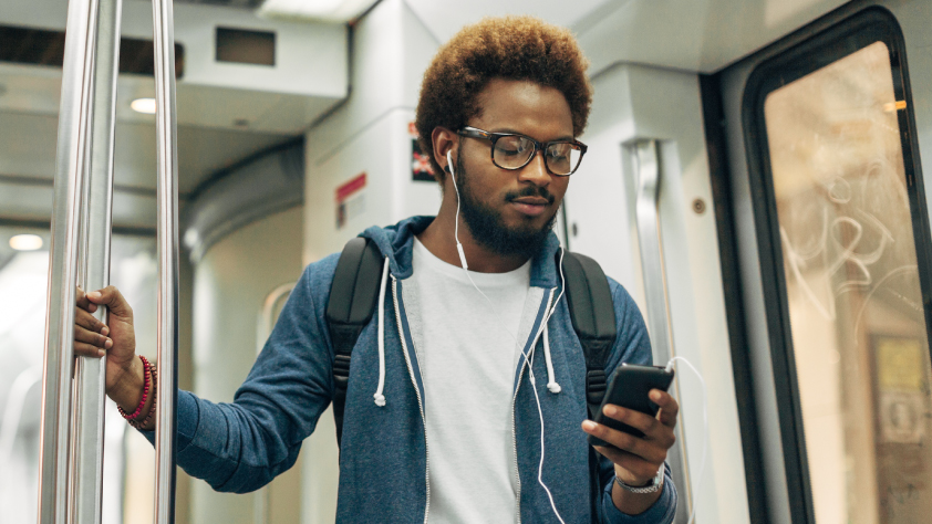 Personne dans un bus, portant des écouteurs et lisant un message sur son téléphone