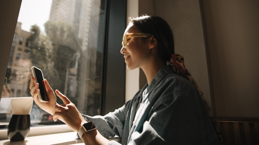 Orang yang duduk di depan jendela sambil membaca pesan dari Vodafone melalui WhatsApp