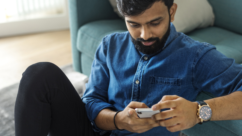 Personne assise par terre contre un canapé lisant un message WhatsApp personnalisé