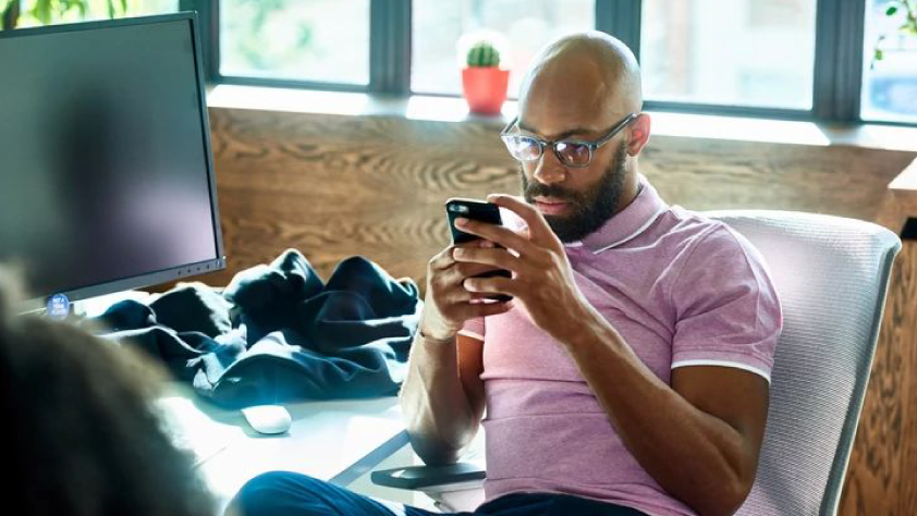 Personne assise à un bureau et regardant son téléphone