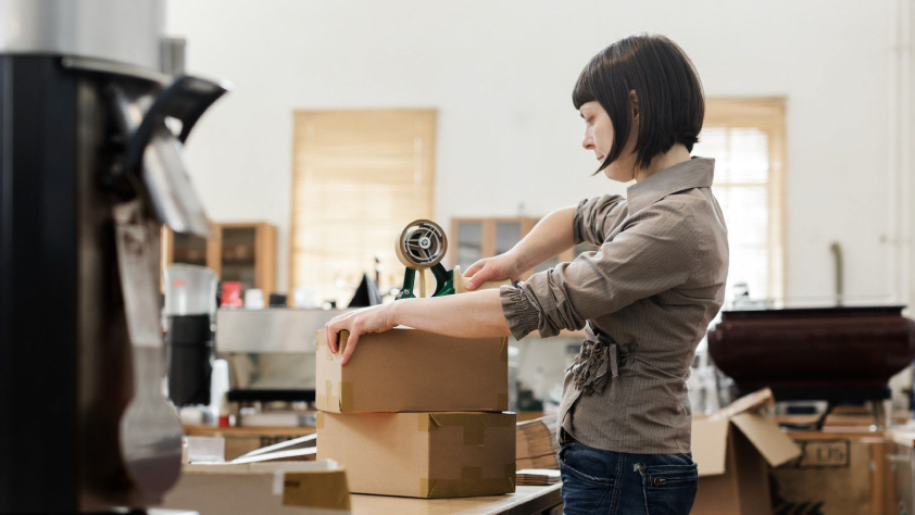 Person packing up home and taping one of the boxes shut