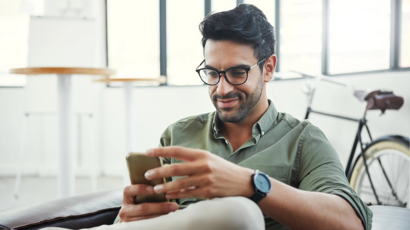 Person sitting in bright office with a bike in the background while reading a business message via WhatsApp on phone