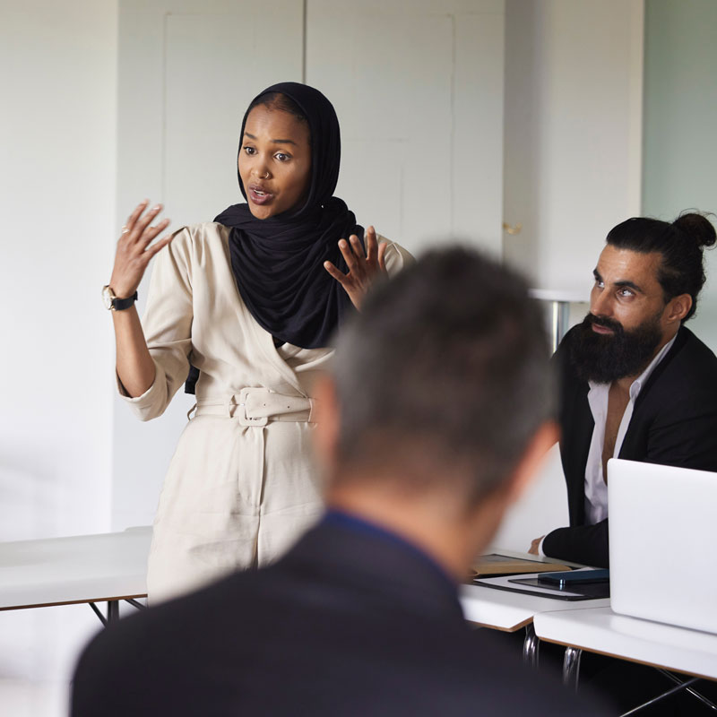 A woman giving a presentation to her coworkers in an office