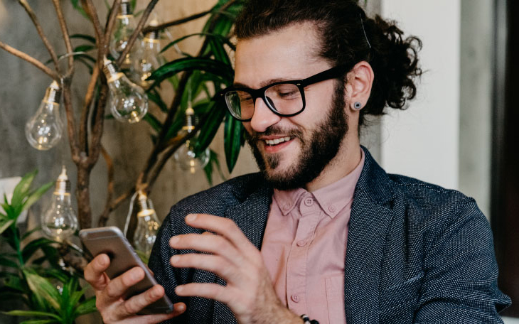 Orang tersenyum melihat telepon sambil mengirim pesan di WhatsApp