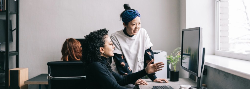 One person showing coworker an example on their computer