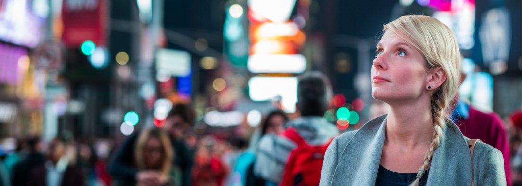 Une personne à Times Square regarde en l’air et fait face à une publicité au milieu de la foule