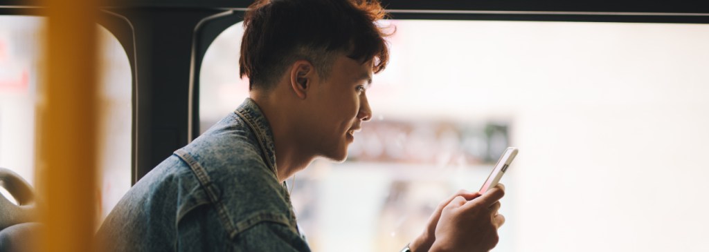Orang duduk di depan jendela bus sambil membaca pesan WhatsApp tentang melakukan pembelian