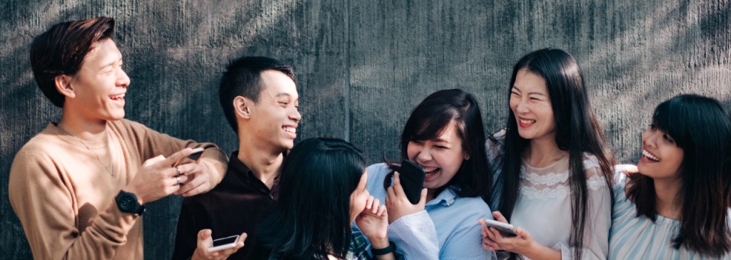 Sekelompok orang berjumlah enam orang sedang tertawa dan memegang telepon