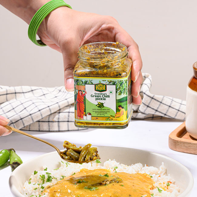 Someone removing pickles from a jar and putting them on a rice dish