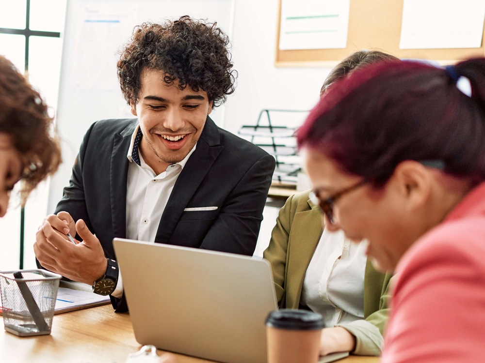 Four people sitting at an office conference table smiling