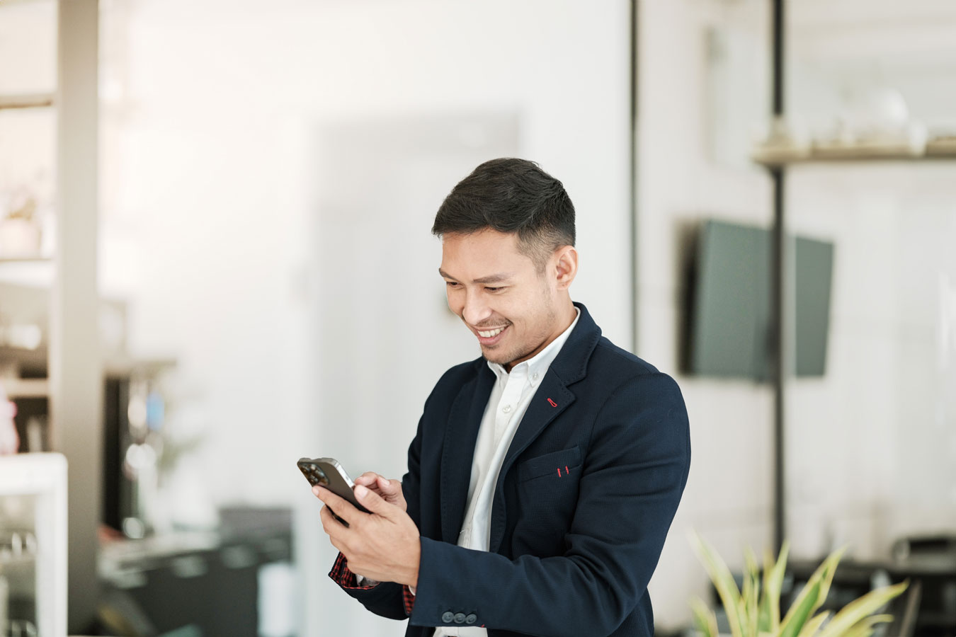 A smiling man in a suit looking at his smartphone