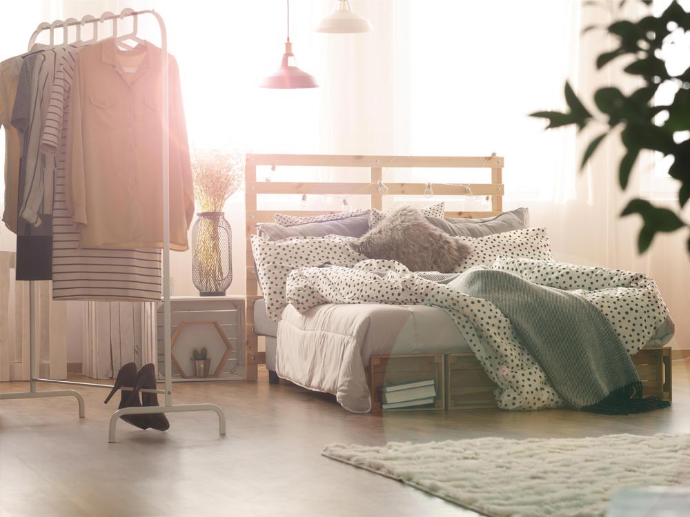 Sala de exposiciones de la empresa Sincere, mostrando una habitación decorada con una cama y un perchero a la izquierda