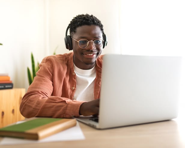 Man smiling and browsing on his laptop