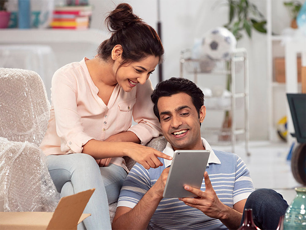 A man and woman both smiling while looking at tablet