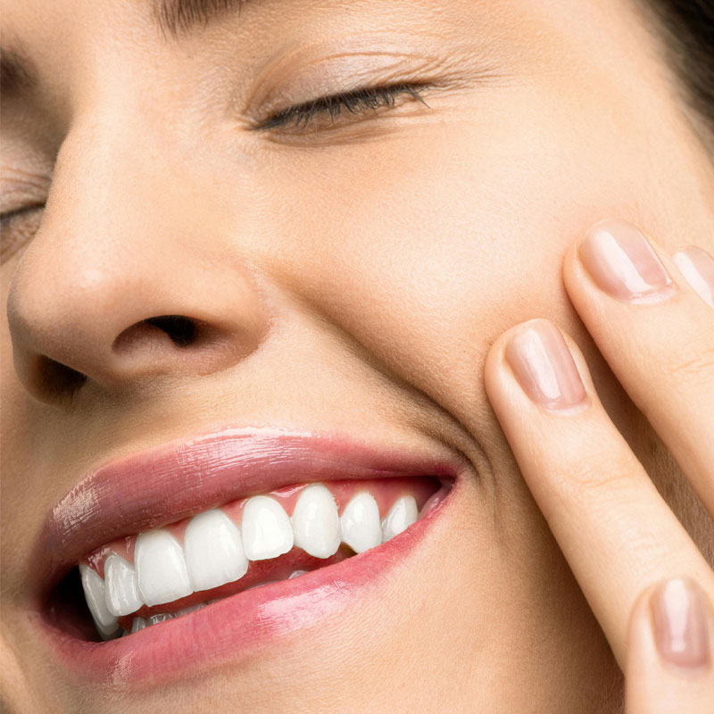 Woman smiling with her eyes closed feeling her face after her skincare routine