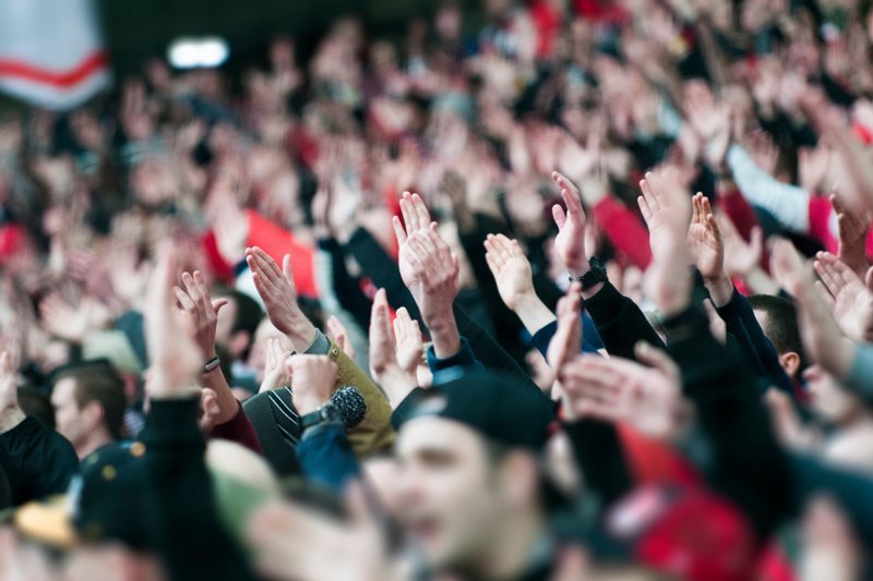 A crowd of football fans raising their hands
