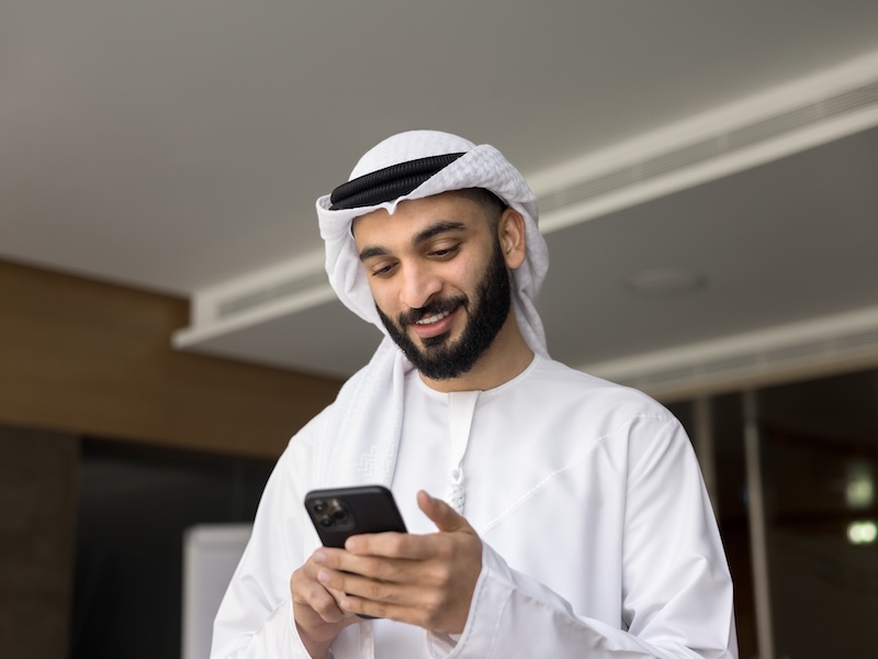 Man wearing keffiyeh looking at his phone