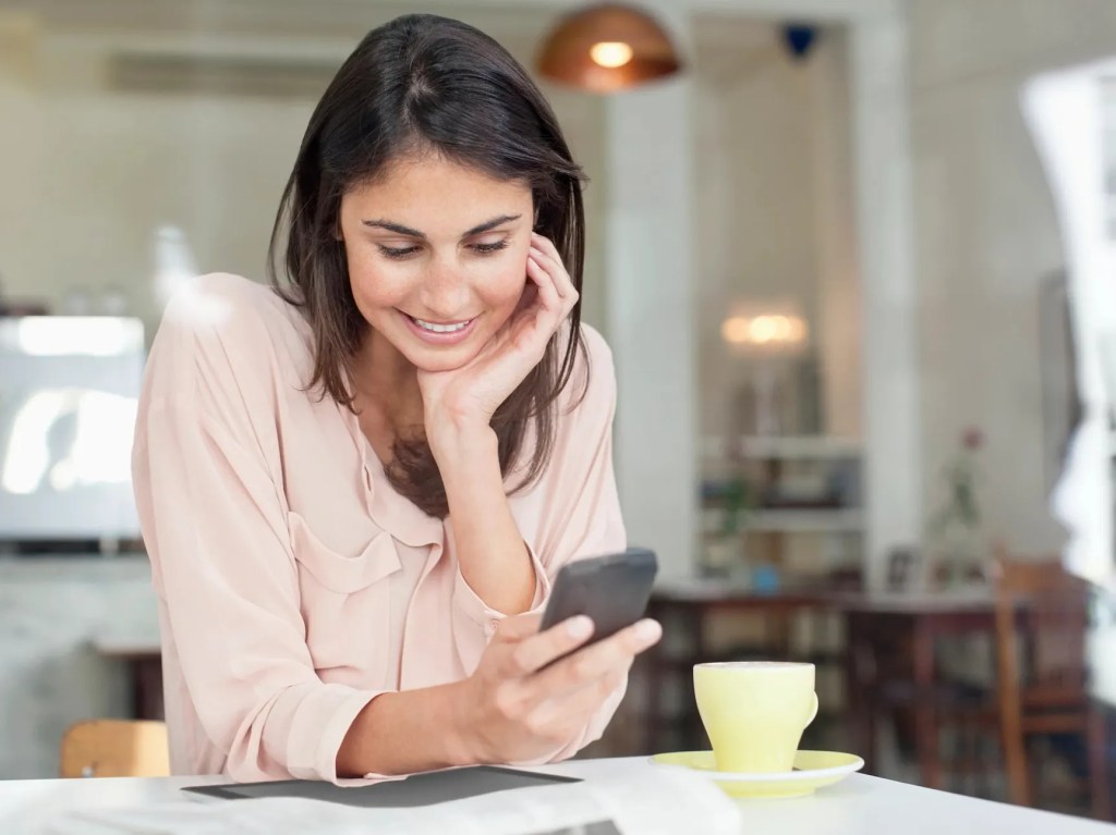 A woman leaning over a table using her phone