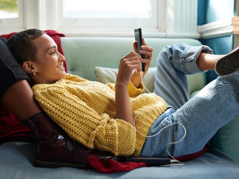 A woman laying on the couch using her phone
