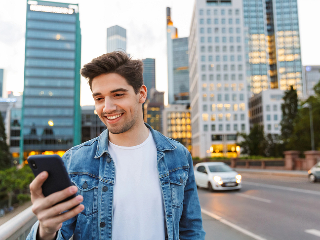 A man outside looking at his phone calling an Uber