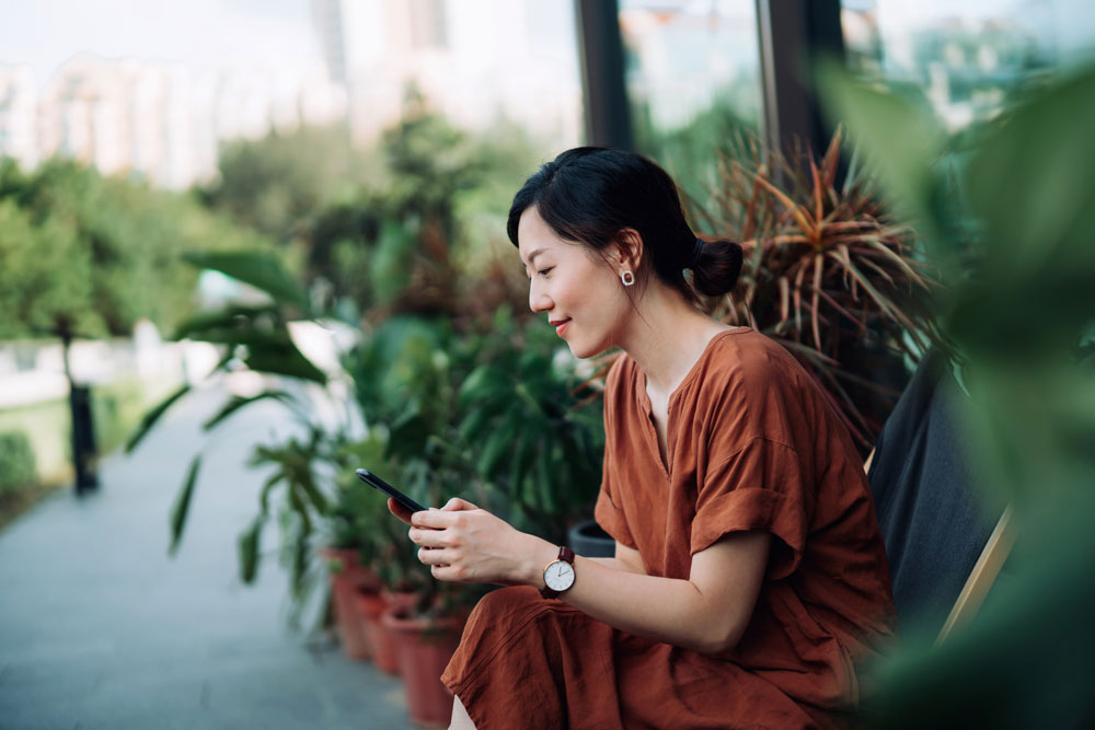 A woman sitting down using her smart phone