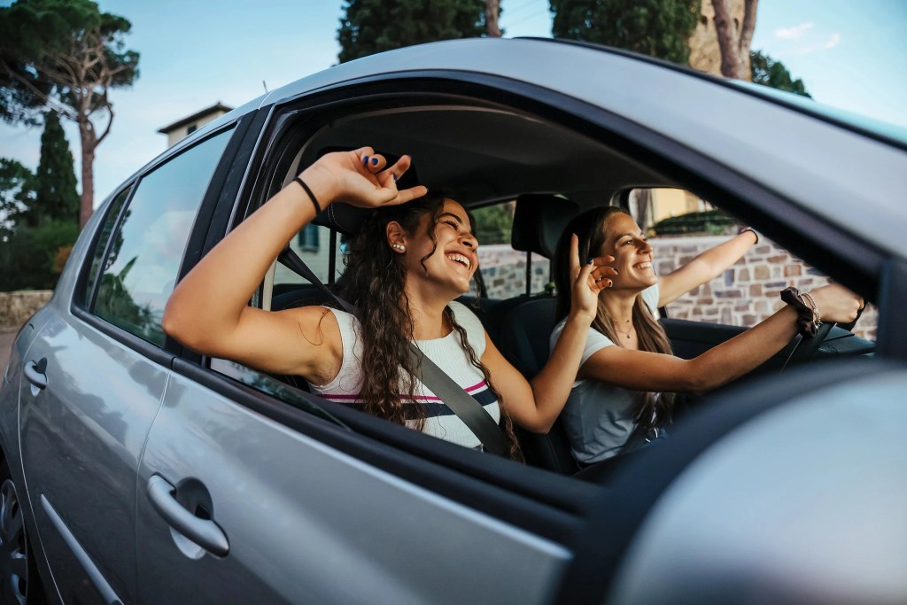 Two women laughing in the front seats of a car