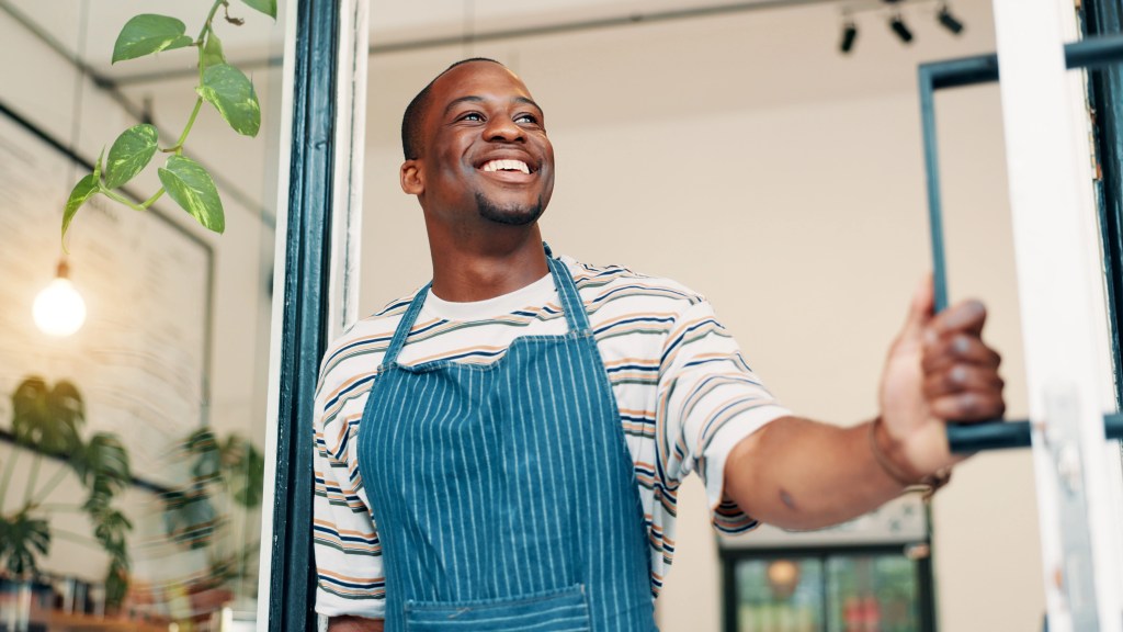 A man smiling while looking out of a doorway