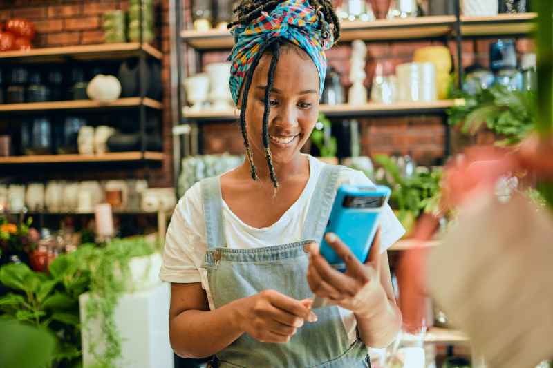 A woman with her hair tied up and smiling while looking down at her phone