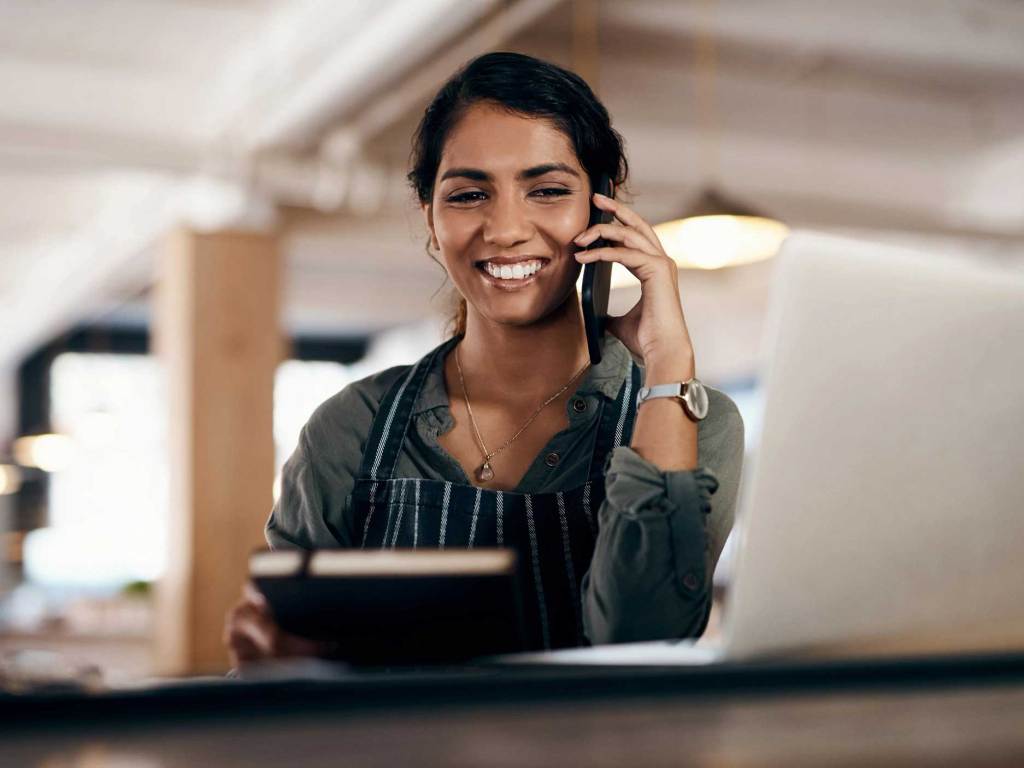 A woman taking a phone call at her desk