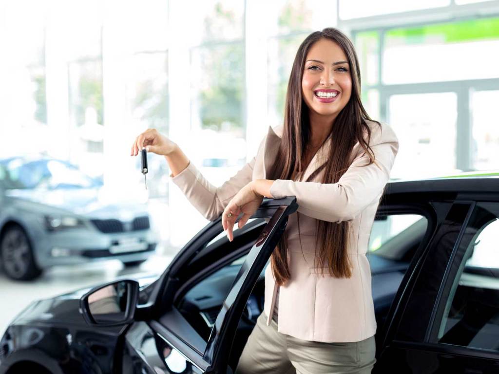 Uma mulher em uma concessionária tirando uma foto com a porta do carro aberta
