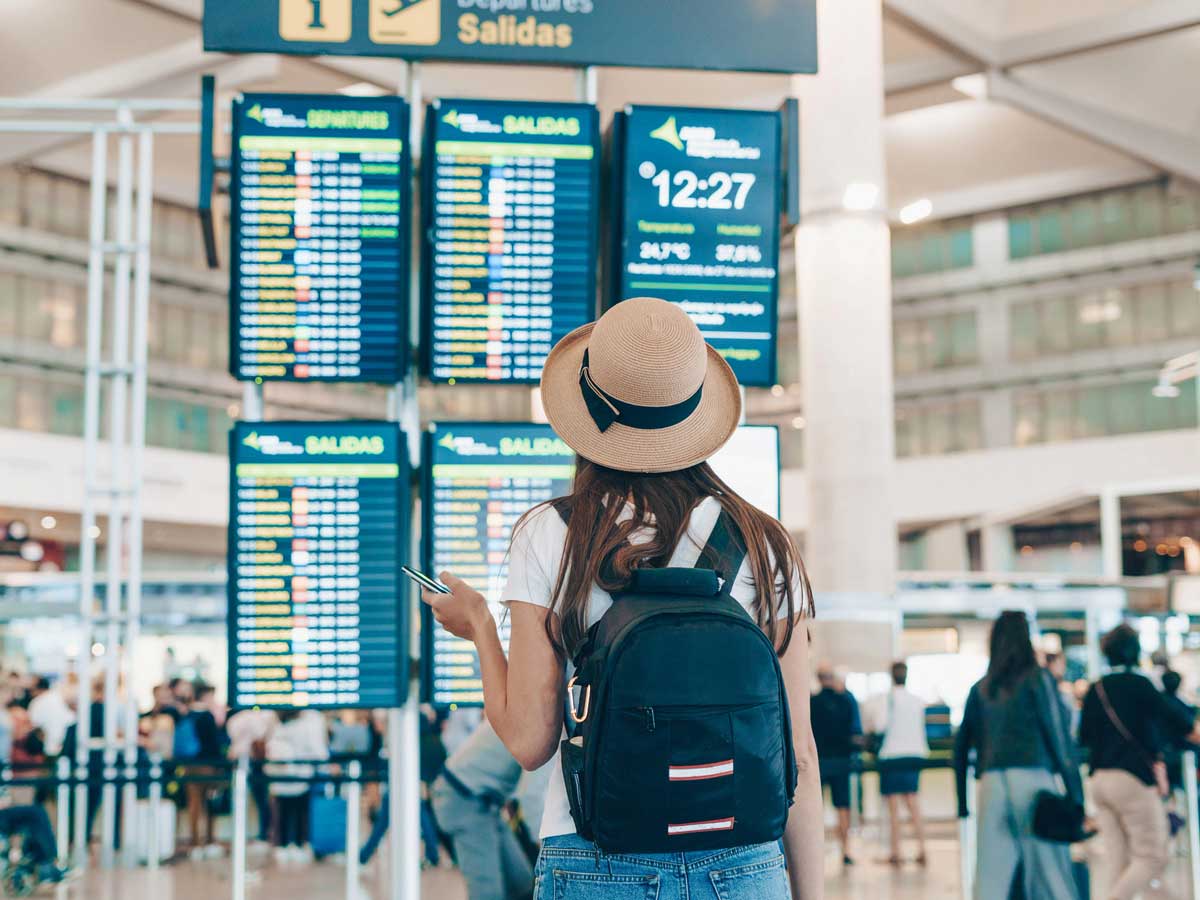 Seorang wanita di bandara melihat monitor waktu keberangkatan