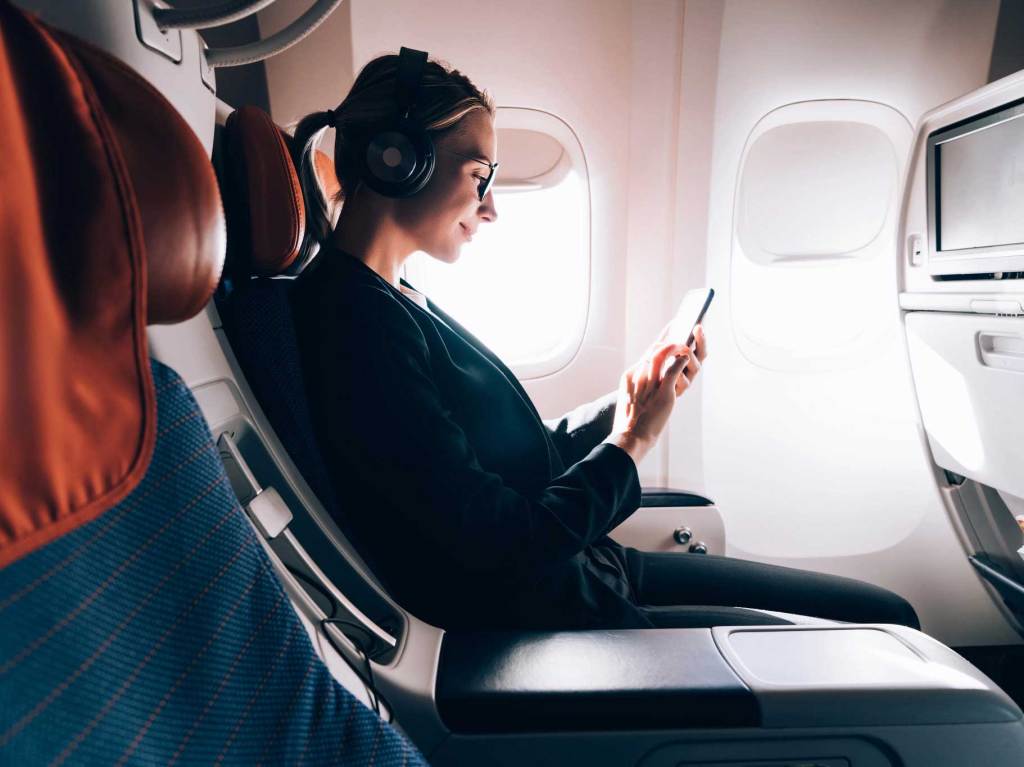 Wanita di pesawat menggunakan telepon pintar