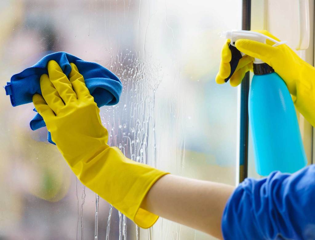 A cleaner wiping a large window