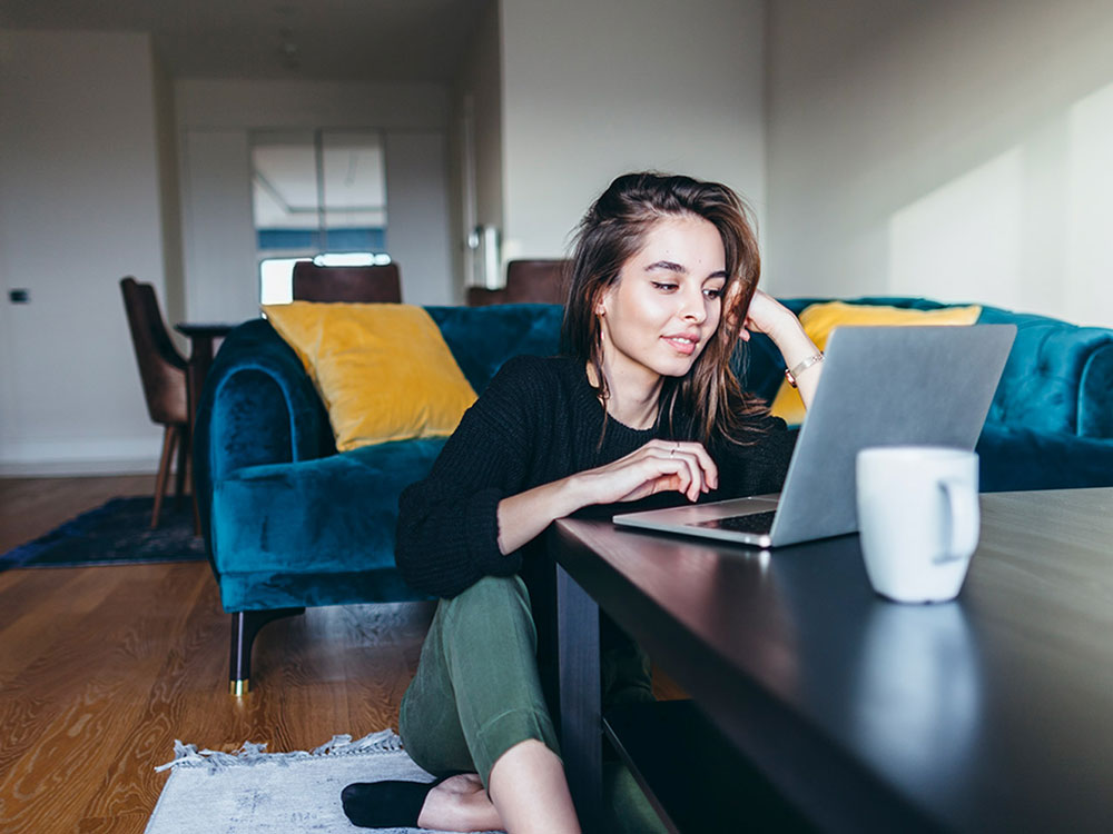 A person sitting on her living room floor using her laptop
