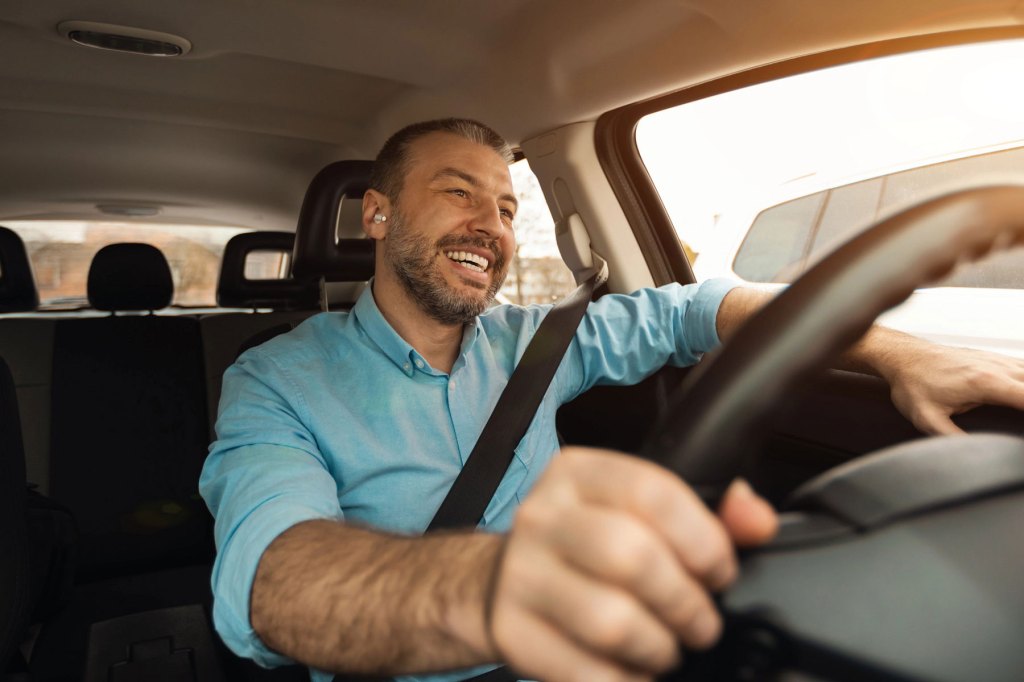 An uber driver smiling and driving to his destination