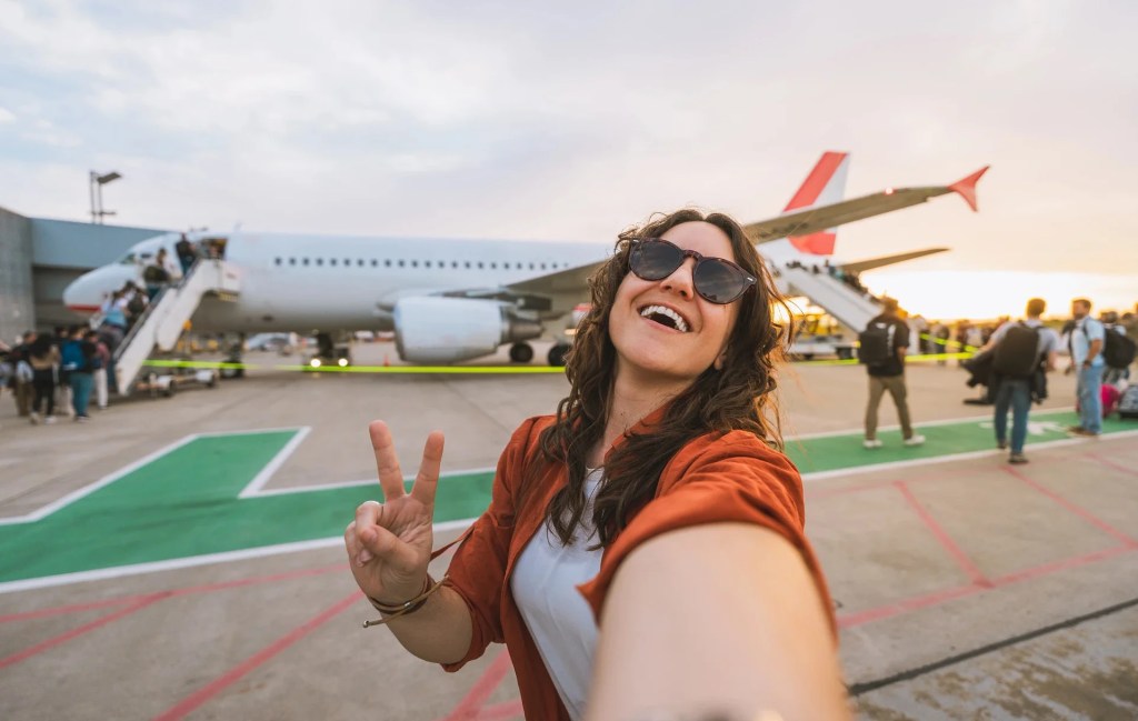 A woman posing for a picture in front of an airplane
