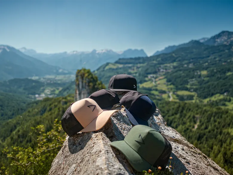 A lineup of apol headwear overlooking mountains