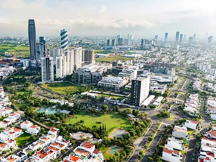 Vista aérea de uma cidade com uma mistura de arranha-céus, áreas verdes e regiões residenciais.