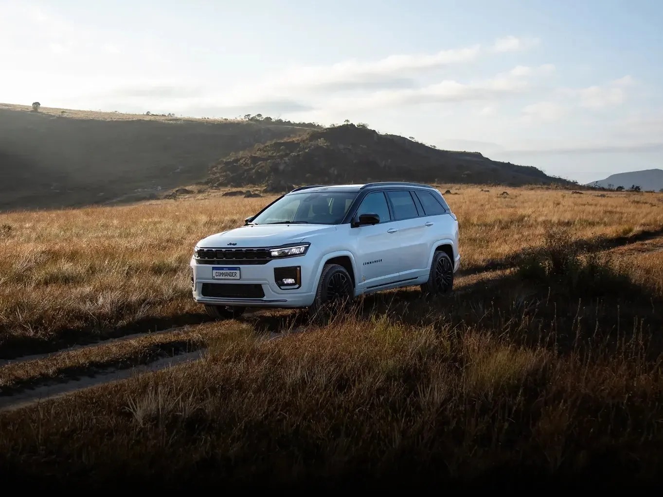 Jeep commander on a dirt road with hills in the background